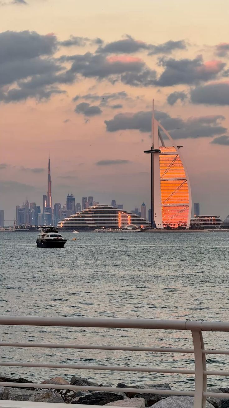 Sunset view of Burj Al Arab with Dubai skyline and Burj Khalifa in the background.