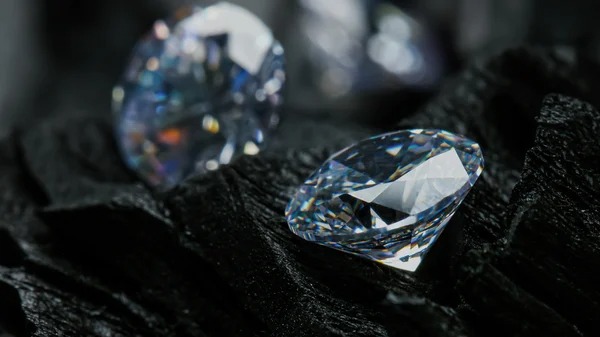 Close-up of a brilliant-cut diamond resting on a dark textured surface, reflecting light beautifully