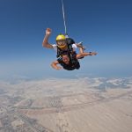 tandem skydive Tandem skydivers freefalling over desert landscapes with the sea in the distance.